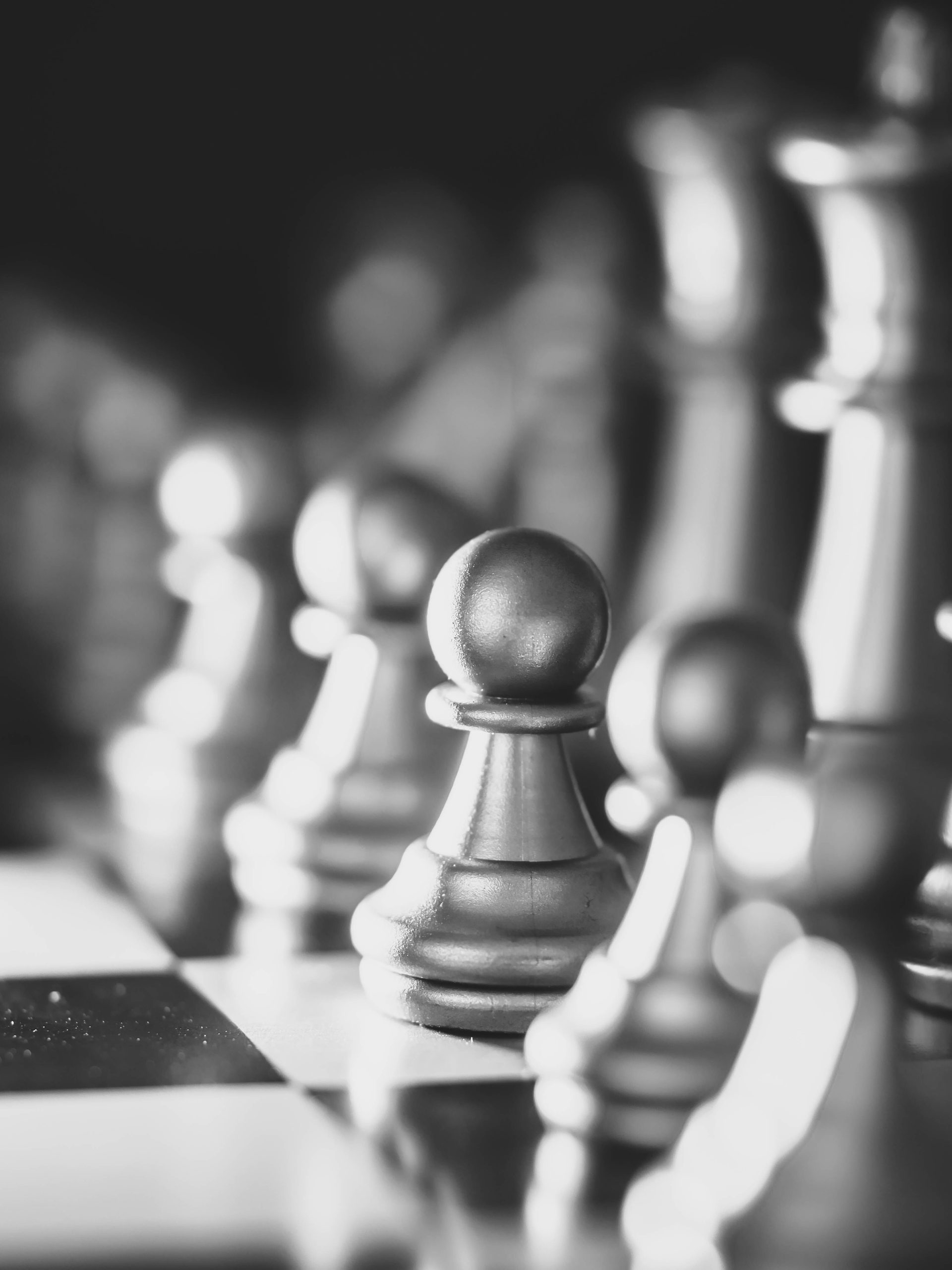 Close-up view of shiny chess pieces reflecting light on a board.
